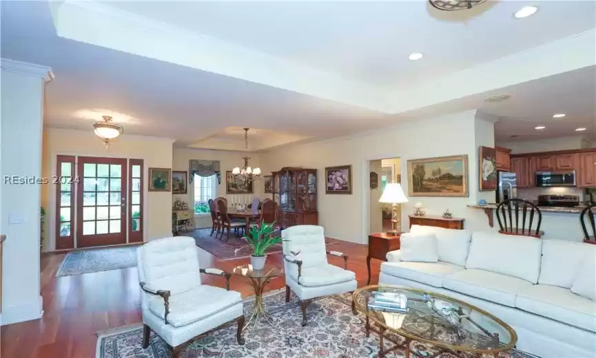 Inviting open floorplan is great for entertaining. Living room with a tray ceiling, ornamental molding, a notable chandelier, and 5