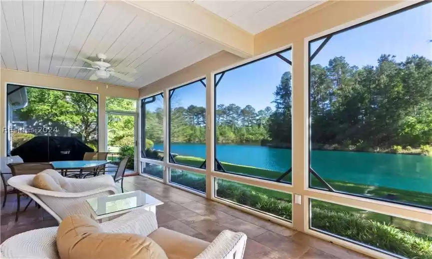 Sunroom / solarium featuring ceiling fan and a water view