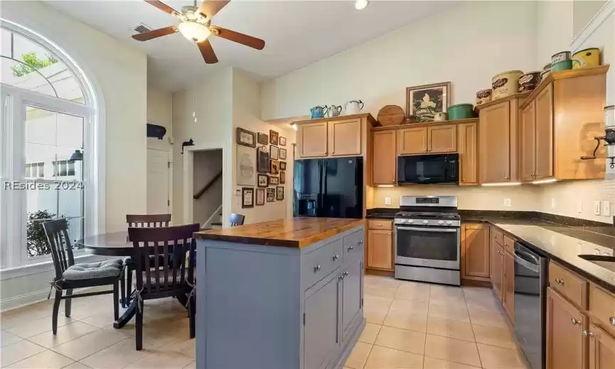 Kitchen with ceiling fan, light tile floors, a kitchen island, gray cabinets, and black appliances