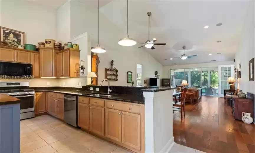 Kitchen featuring light tile flooring, kitchen peninsula, appliances with stainless steel finishes, sink, and ceiling fan