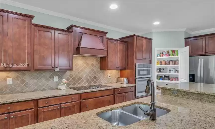 Kitchen with backsplash, stainless steel appliances, light stone countertops, and custom exhaust hood