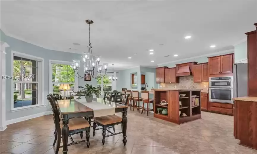 Dining room with sink, light tile flooring, crown molding, and an inviting chandelier