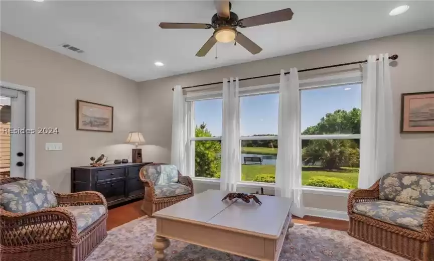 Living room with ceiling fan, a wealth of natural light, and dark wood-type flooring