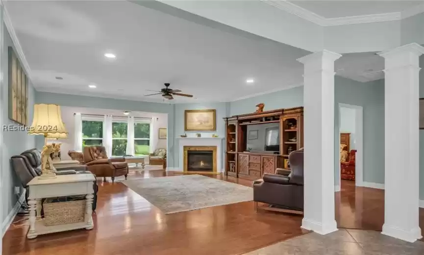 Tiled living room featuring ornamental molding, ceiling fan, and decorative columns