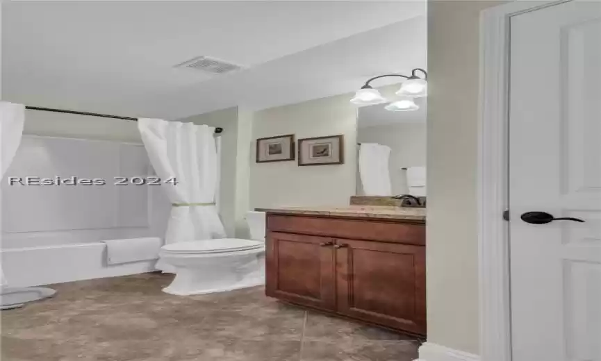 Full bathroom with shower / tub combo with curtain, oversized vanity, tile floors, and toilet