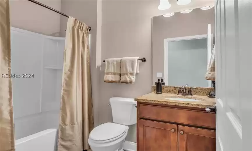 Full bathroom with oversized vanity, shower / bath combination with curtain, and toilet