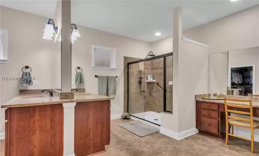 Bathroom with tile floors, vanity, and a shower with door