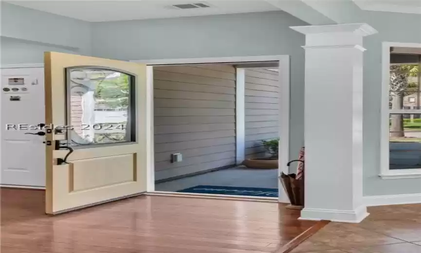 Entryway featuring a healthy amount of sunlight, dark wood-type flooring, ornate columns, and crown molding