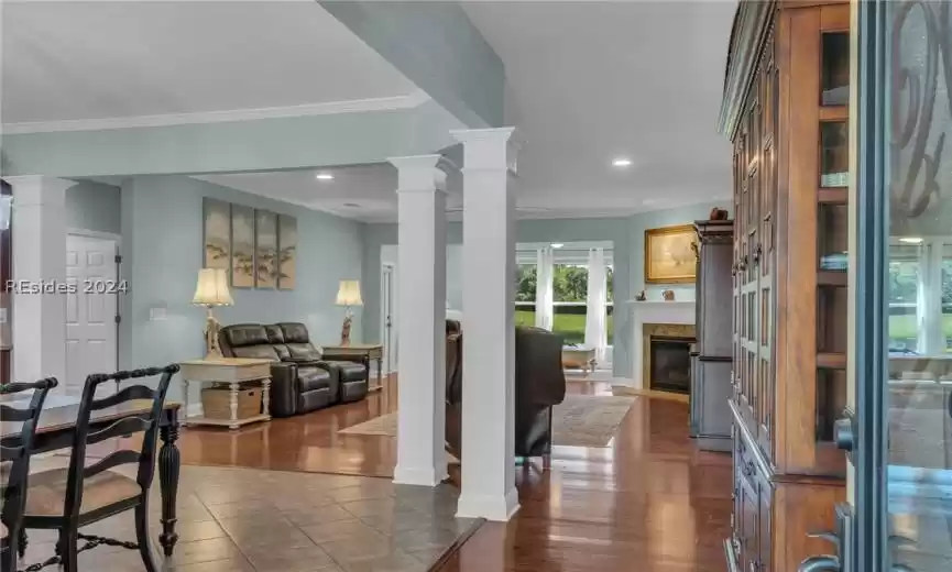 Foyer with dark tile flooring, crown molding, and decorative columns