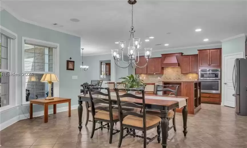 Tiled dining space with a notable chandelier and crown molding