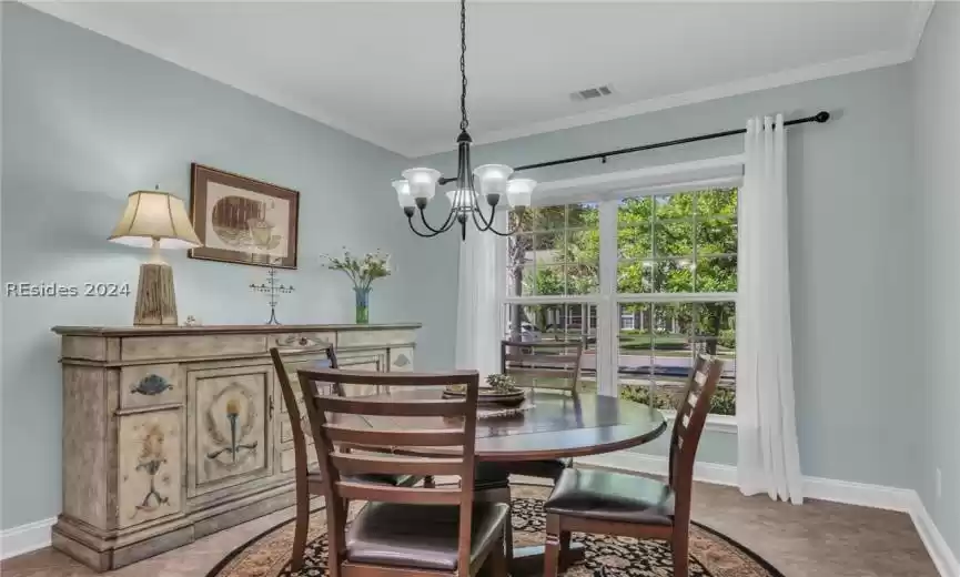 Tiled dining space featuring a notable chandelier and ornamental molding