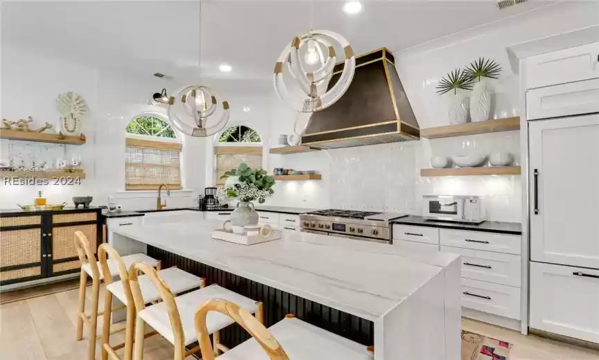 Kitchen featuring wine cooler, pendant lighting, tasteful backsplash, light hardwood / wood-style flooring, and stainless steel gas range