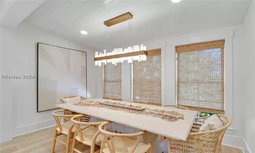 Kitchen with white paneled appliances, white cabinetry, hanging light fixtures, light hardwood / wood-style flooring, and premium range hood