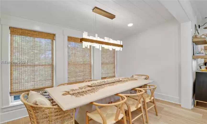 Dining room with lofted ceiling, plenty of natural light, a chandelier, and light wood-type flooring