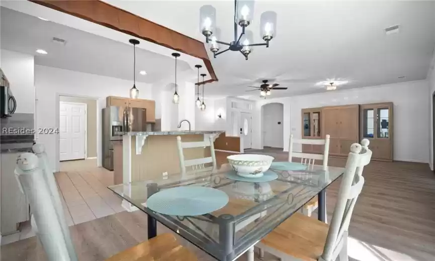 Dining area featuring ceiling fan with notable chandelier, LVP