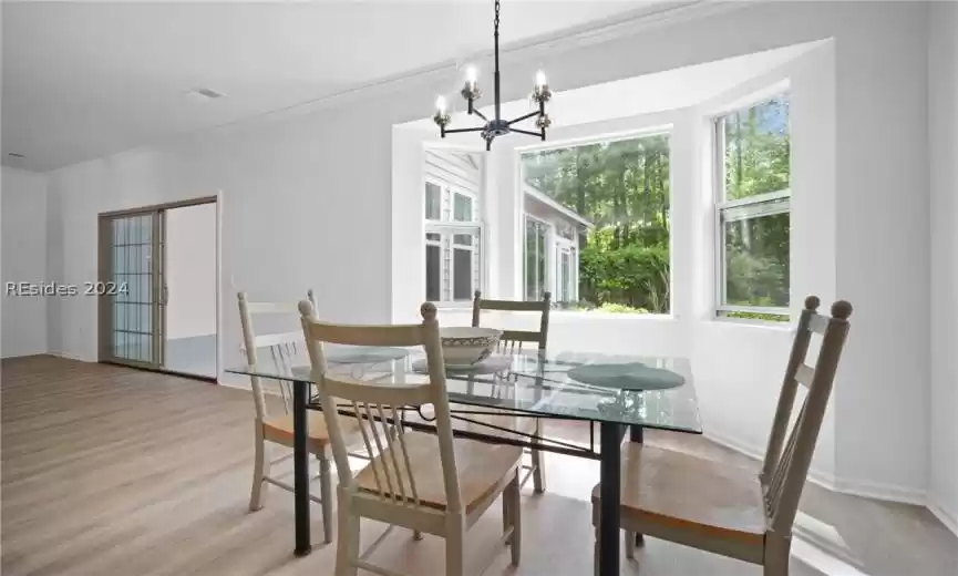 Dining space featuring a chandelier, crown molding, and LVP flooring