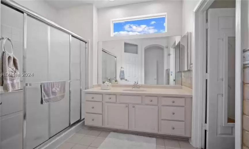 Owner's bathroom featuring walk in shower, large vanity, and tile floors