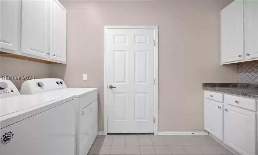 Laundry area featuring cabinets, separate washer and dryer, and light tile floors