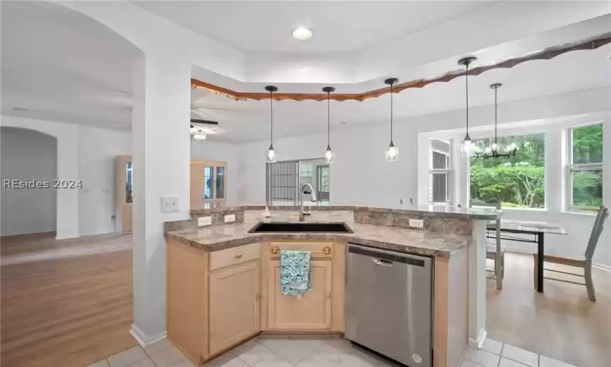 Kitchen with stainless steel dishwasher, sink, light tile flooring, and pendant lighting