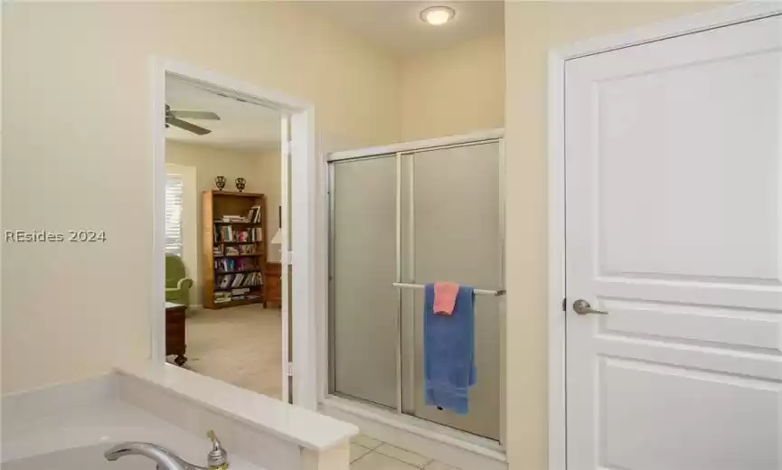 Bathroom with tile flooring, a shower with shower door, and ceiling fan