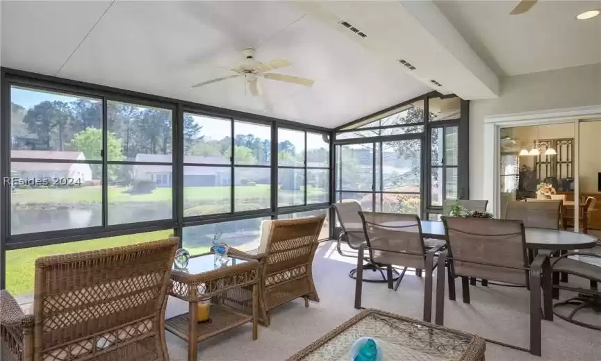 Sunroom featuring vaulted ceiling, ceiling fan with notable chandelier, and a water view