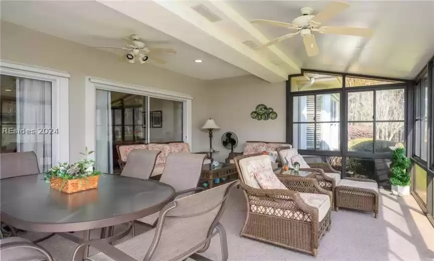 Sunroom / solarium with ceiling fan and lofted ceiling with beams