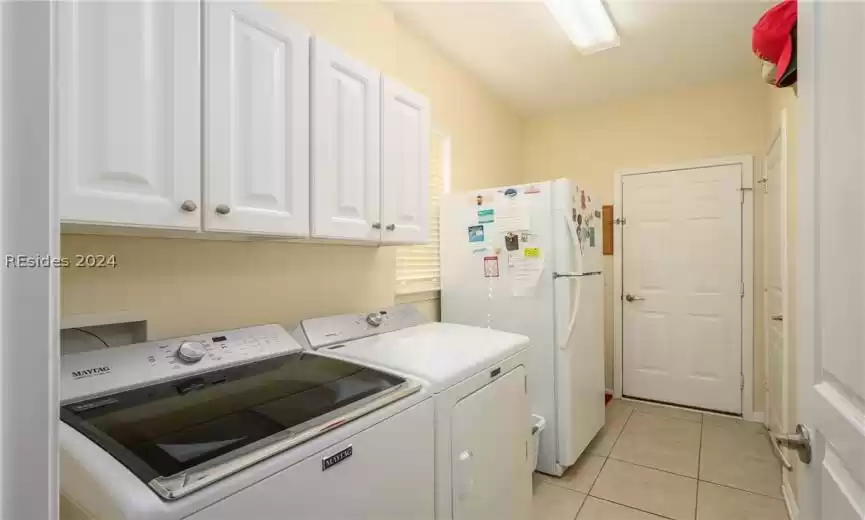 Laundry area with light tile floors, hookup for a washing machine, cabinets, and washer and clothes dryer