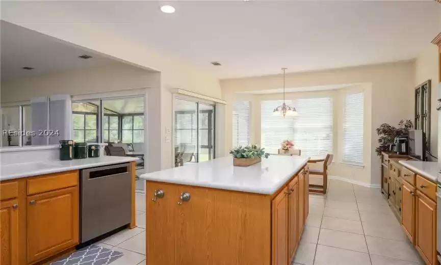 Kitchen with plenty of natural light, stainless steel dishwasher, a notable chandelier, a kitchen island, and pendant lighting