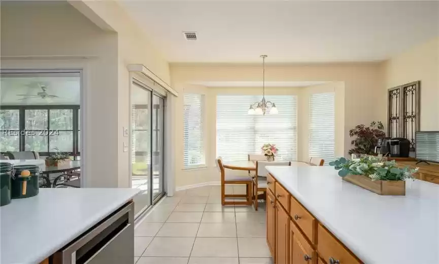 Kitchen with light tile floors, pendant lighting, ceiling fan with notable chandelier, and dishwasher