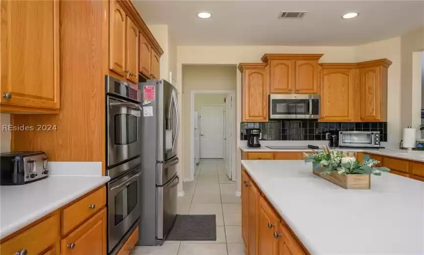 Kitchen featuring light tile flooring, stainless steel appliances, and backsplash