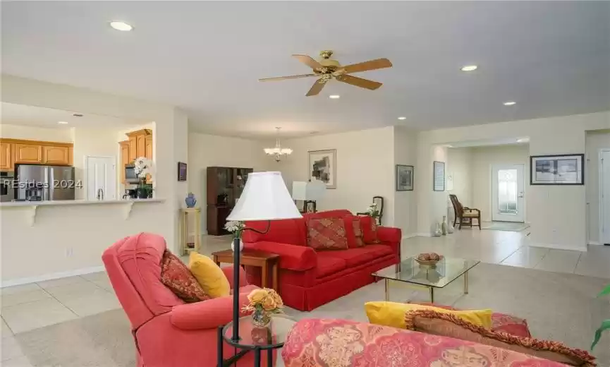 Living room featuring ceiling fan with notable chandelier and light tile floors