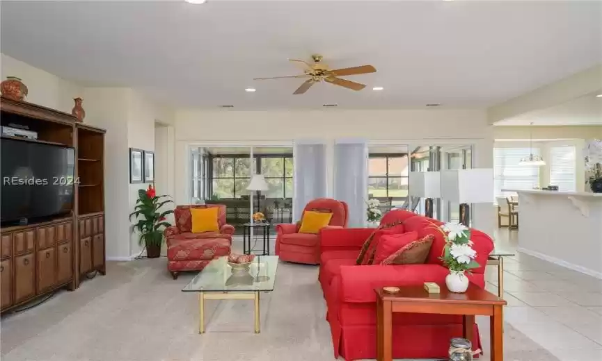 Carpeted living room with ceiling fan with notable chandelier