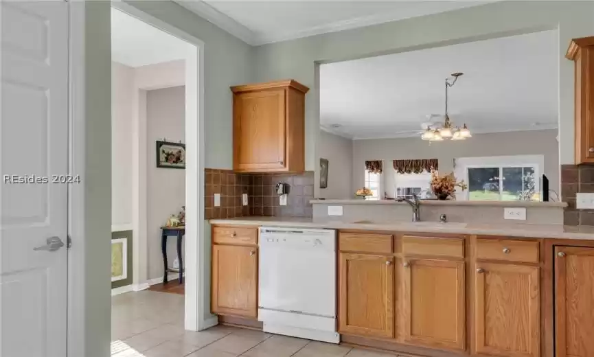 Kitchen with dishwasher, backsplash, sink, and light tile floors