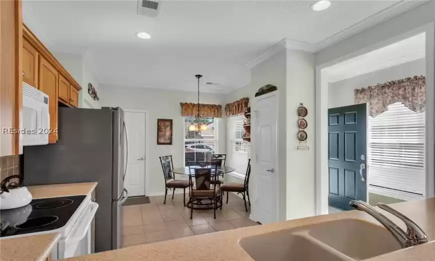 Kitchen with white appliances, light tile floors, decorative light fixtures, sink, and a chandelier