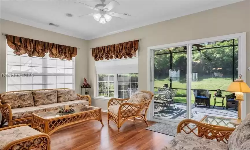 Living room with ceiling fan, ornamental molding, and wood-type flooring