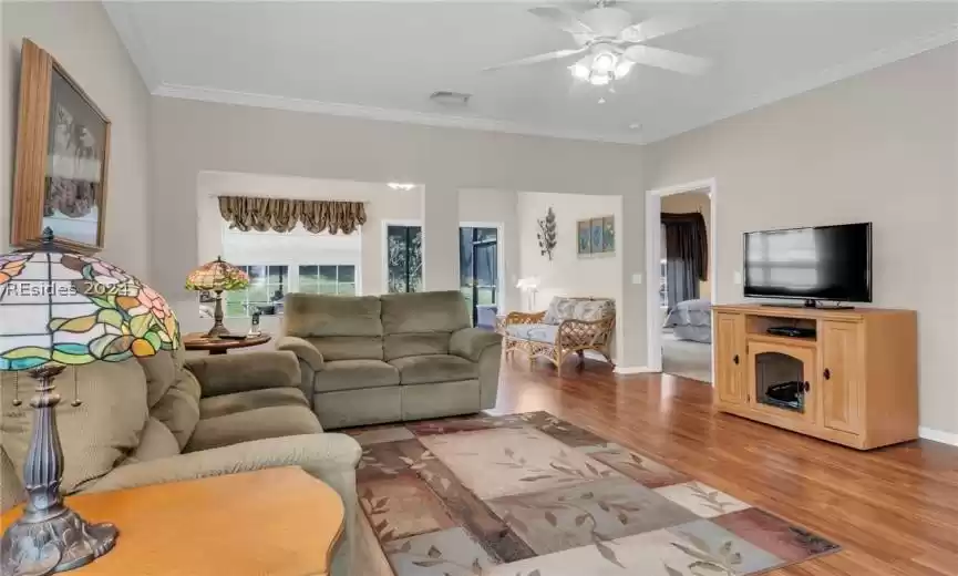 Living room with ceiling fan, light hardwood / wood-style flooring, and ornamental molding