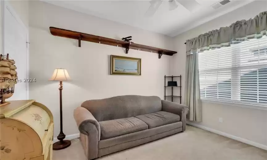 Carpeted den with ceiling fan