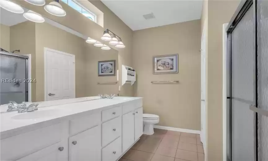 Bathroom featuring toilet, double sink, vanity and tile floors