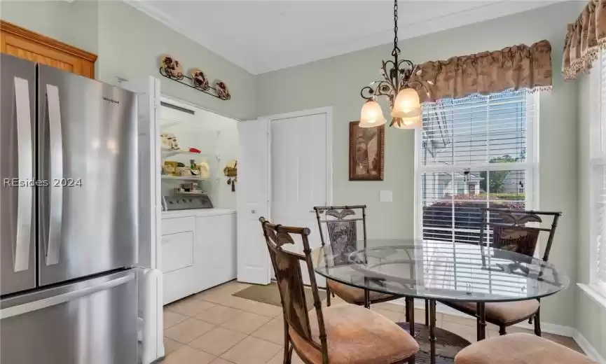 Dining space with laundry area, ornamental molding, a chandelier, and light tile floors