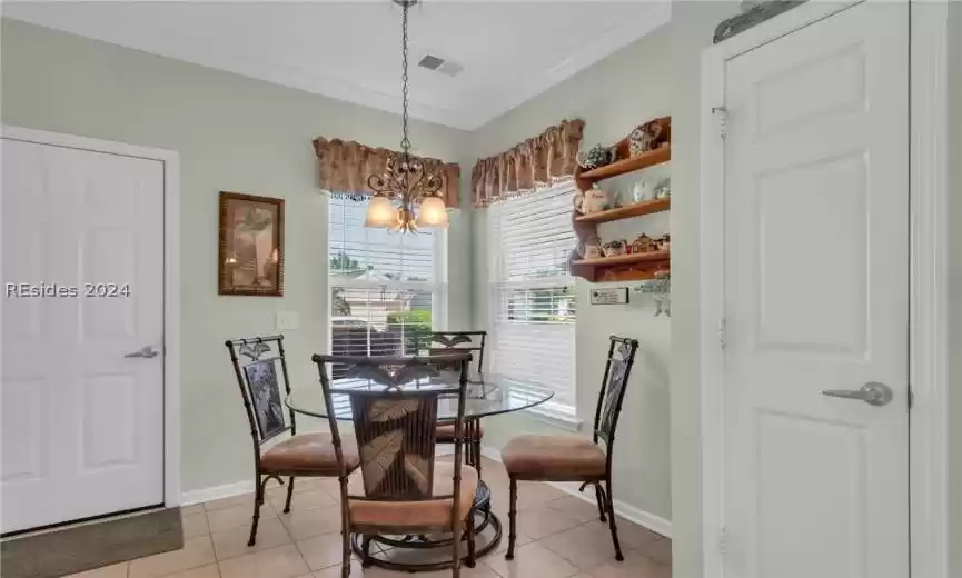 Tiled dining area featuring a chandelier and crown molding