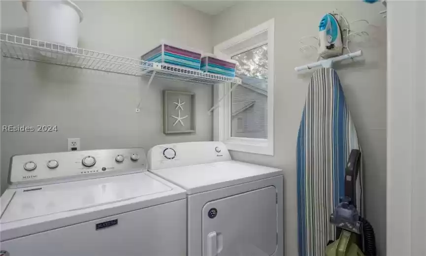 Washer and dryer with storage rack above plus vacuum and other laundry needs.