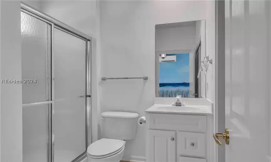Bathroom featuring a shower with shower door, toilet, oversized vanity, and a wall mounted AC