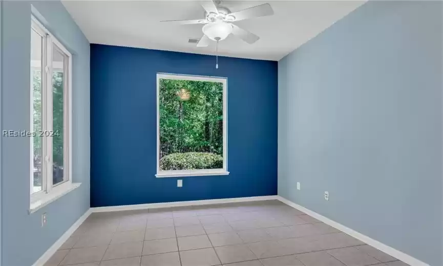 Unfurnished room with ceiling fan and light tile flooring