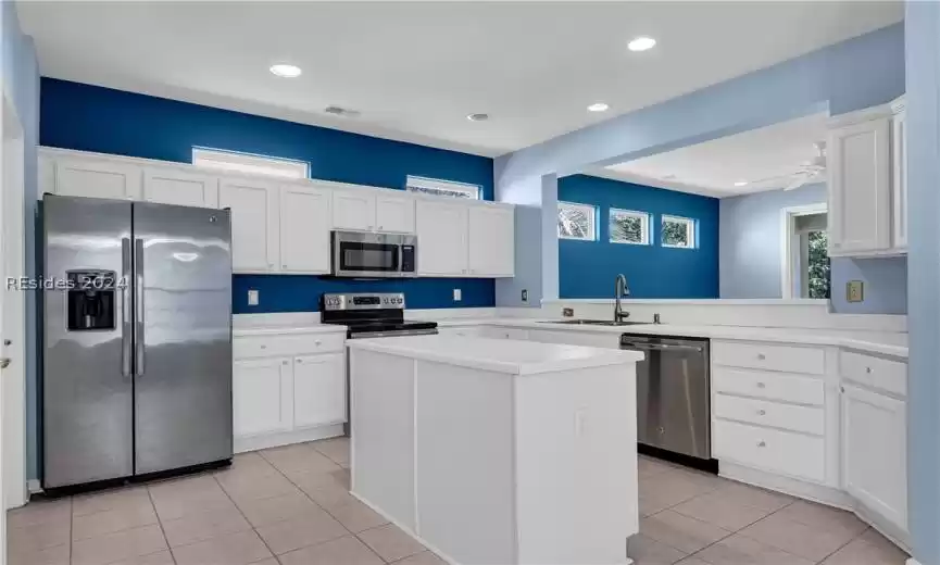 Kitchen with ceiling fan, stainless steel appliances, white cabinetry, a center island, and light tile floors