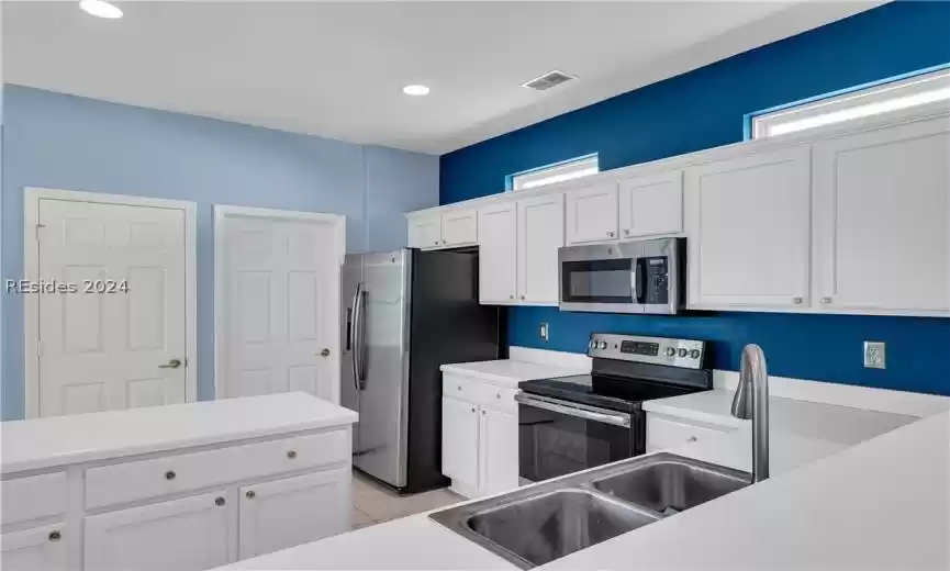 Kitchen featuring white cabinets, sink, appliances with stainless steel finishes, and light tile floors