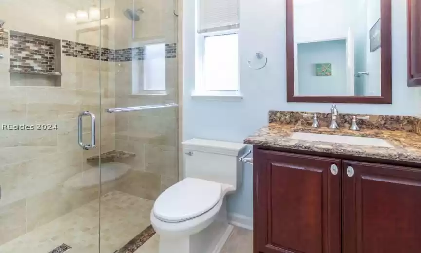 Newly remodeled guest bathroom with custom tile walk-in shower and granite vanity.