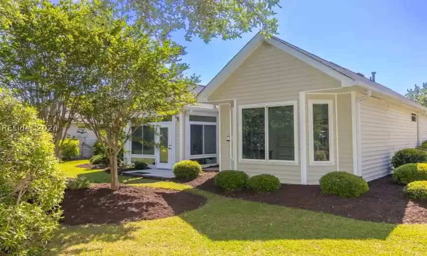 View of the rear of the home featuring lots of windows and mature landscaping.