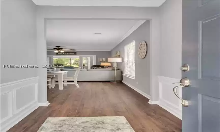 Entryway featuring ceiling fan, crown molding, and dark wood-type flooring