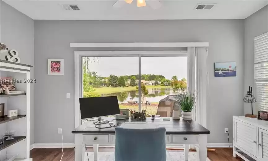 Home office with ceiling fan, a wealth of natural light, and dark wood-type flooring