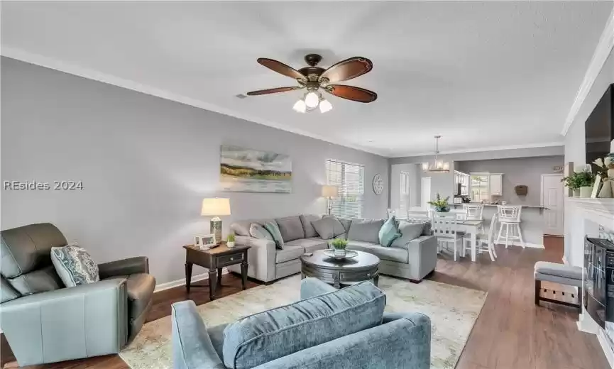 Living room with ceiling fan with notable chandelier, a textured ceiling, hardwood / wood-style floors, and ornamental molding